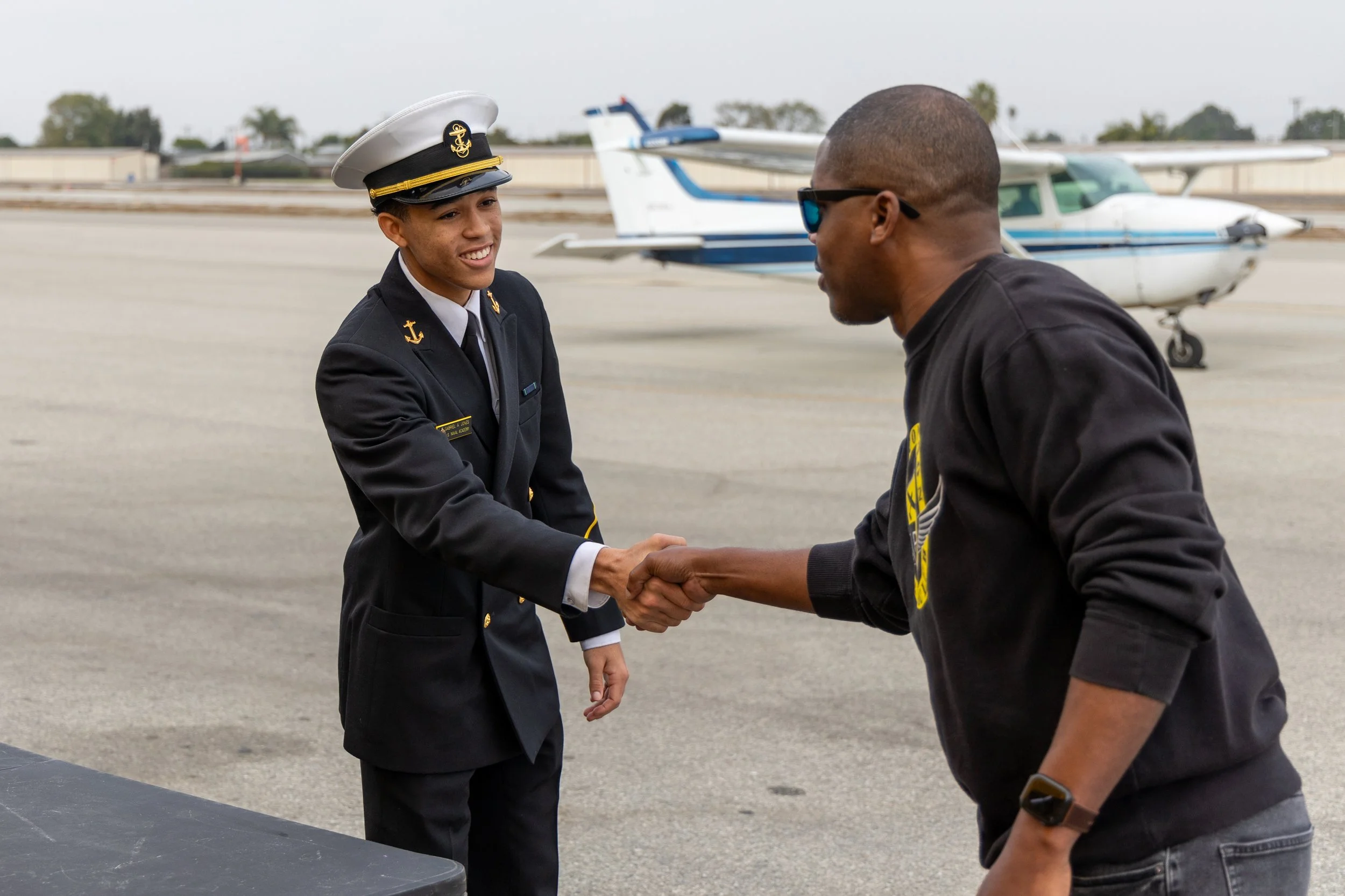 Fly Compton Foundation cadet in uniform shaking hands with a mentor on the airfield