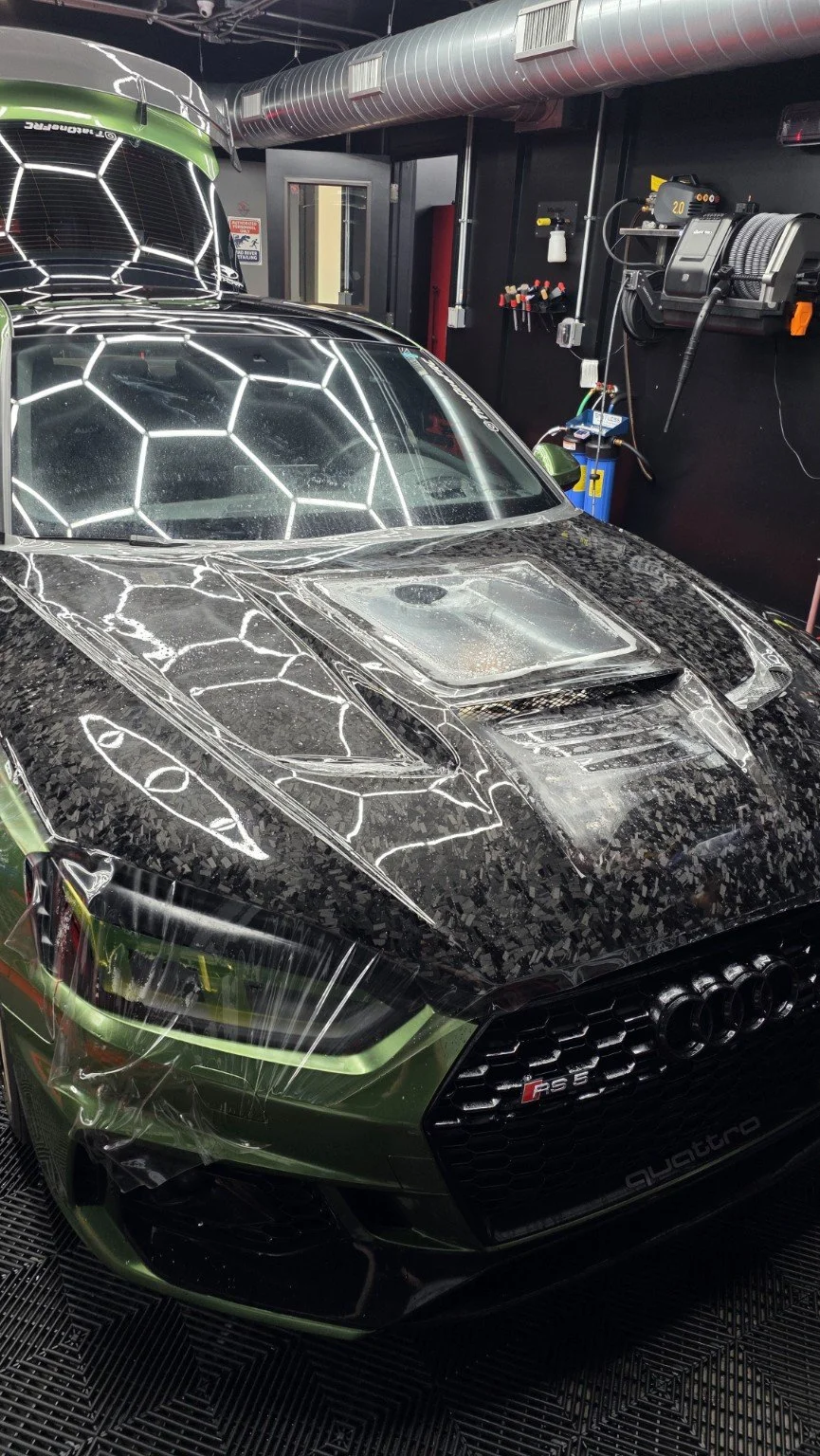 Green Audi RS5 with paint protection film being fitted over its forged carbon hood at Mad River Detailing