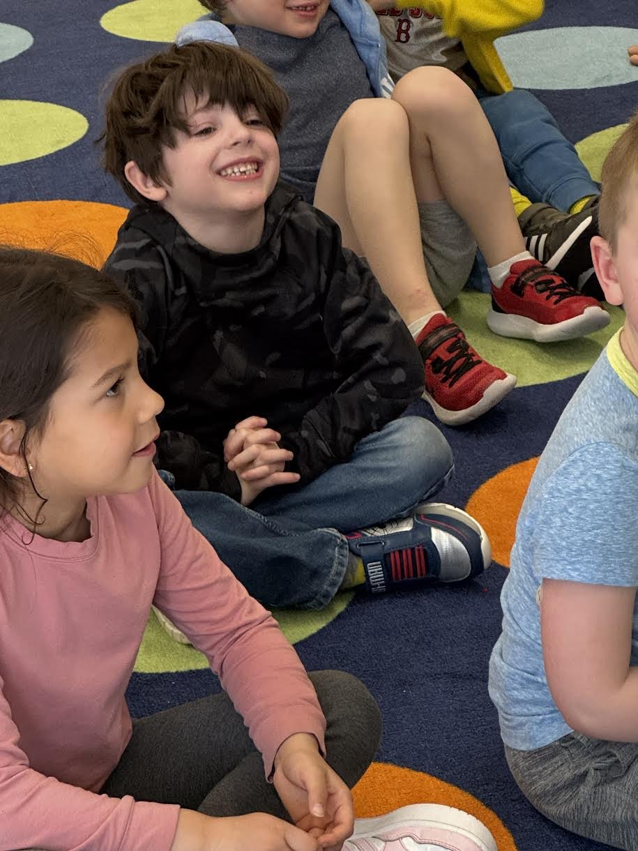 a young student sitting cross legged smiling