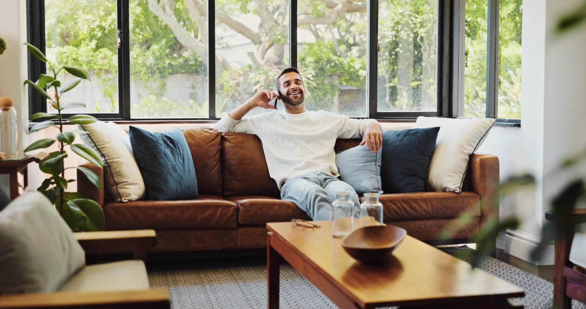 A homeowner smiling on a phone call in his living room
