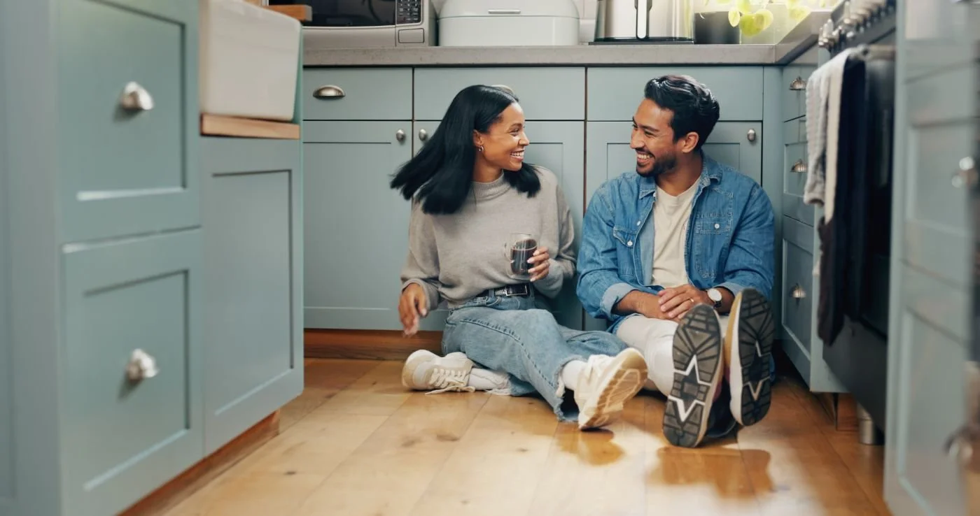 A couple sharing coffee on the kitchen floor of their home