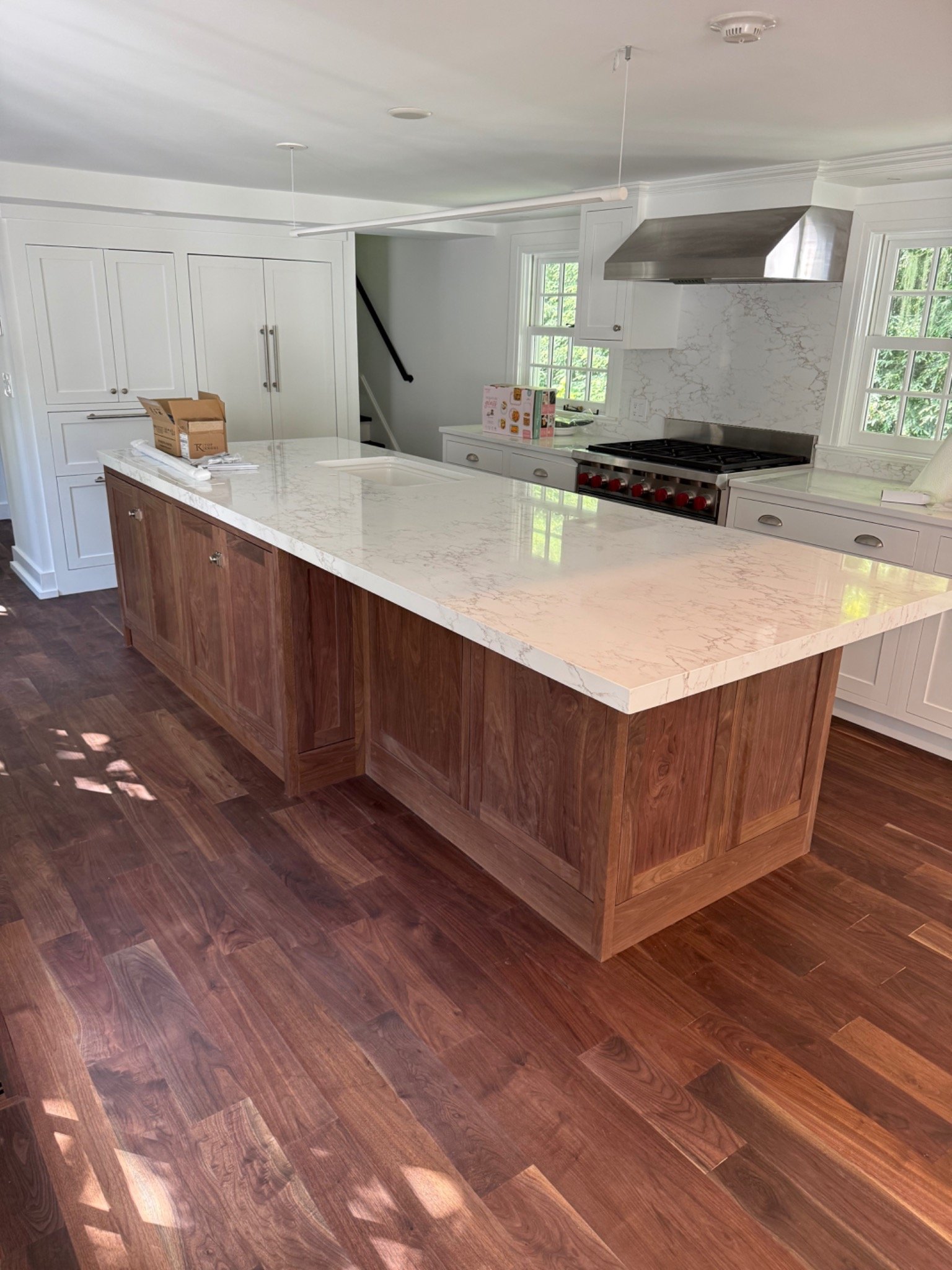 White kitchen cabinetry with a wood island and stone countertop