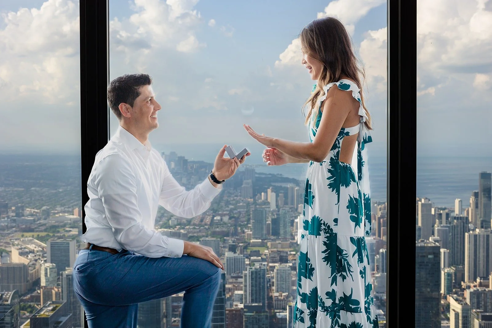 Couple embracing with panoramic Chicago skyline at Willis Tower 99th floor — proposal photography by The Proposal Studios