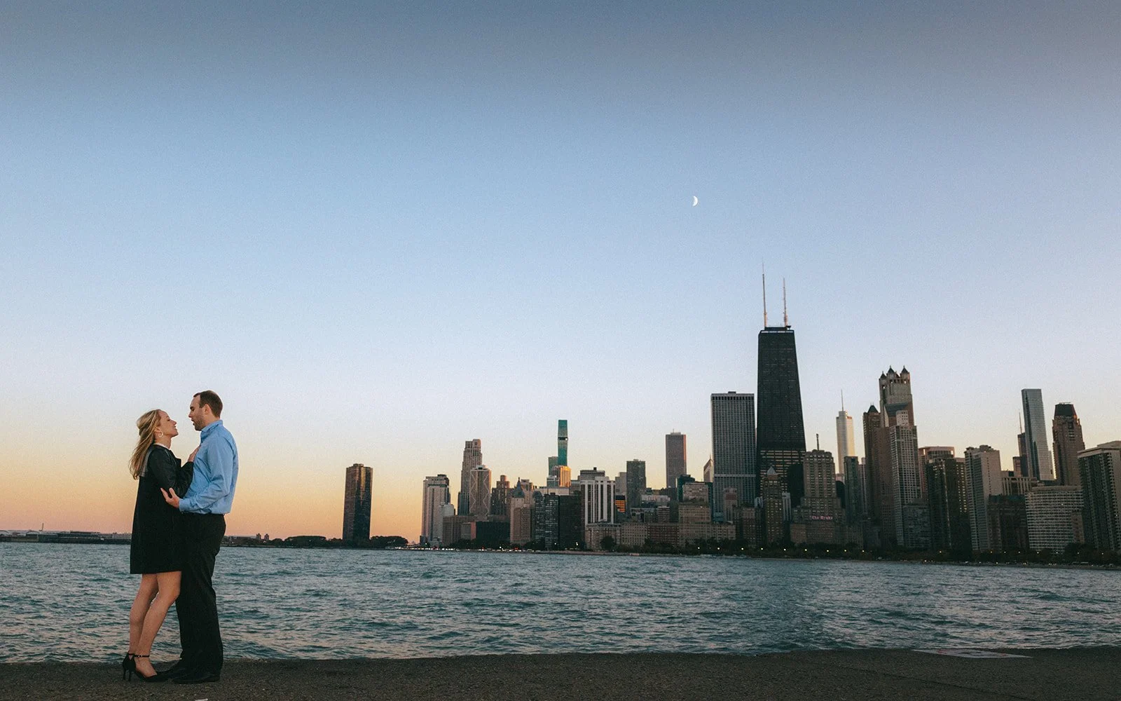 Couple portrait at North Avenue Beach with Chicago skyline and Lake Michigan at dusk — cinematic proposal photography