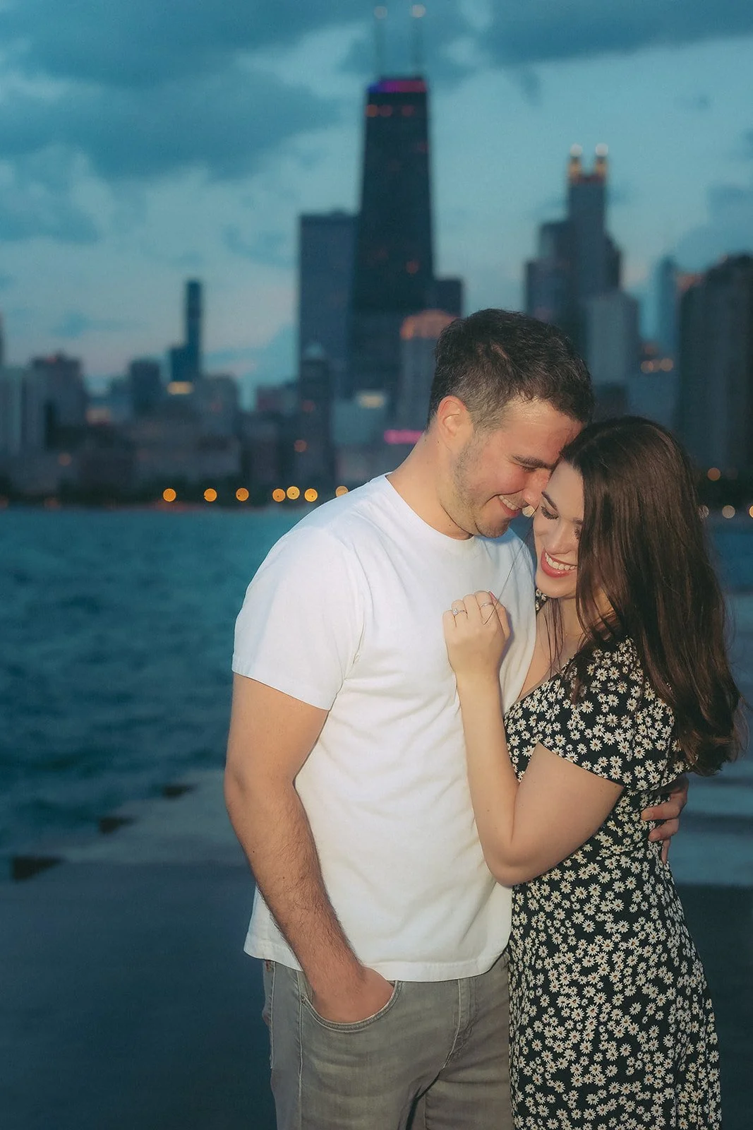 Couple on North Avenue Beach at golden hour with Chicago skyline behind them — proposal and engagement photography by The Proposal Studios