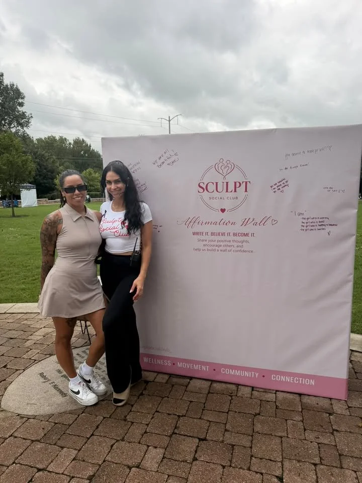 Guests posing in front of a Sculpt Social Club backdrop