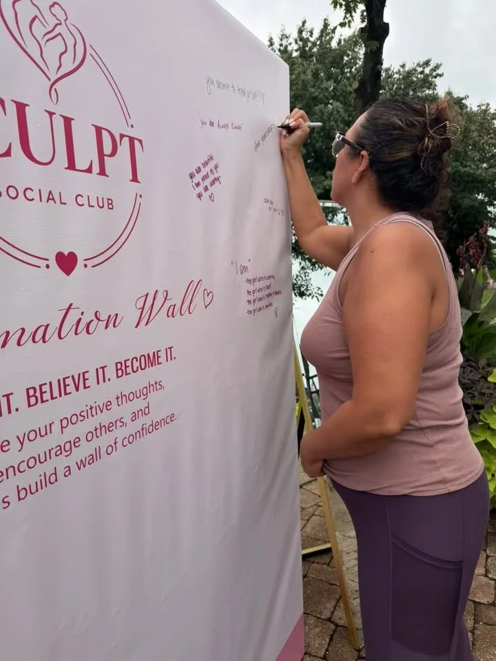 Guest writing on a printed affirmation wall backdrop