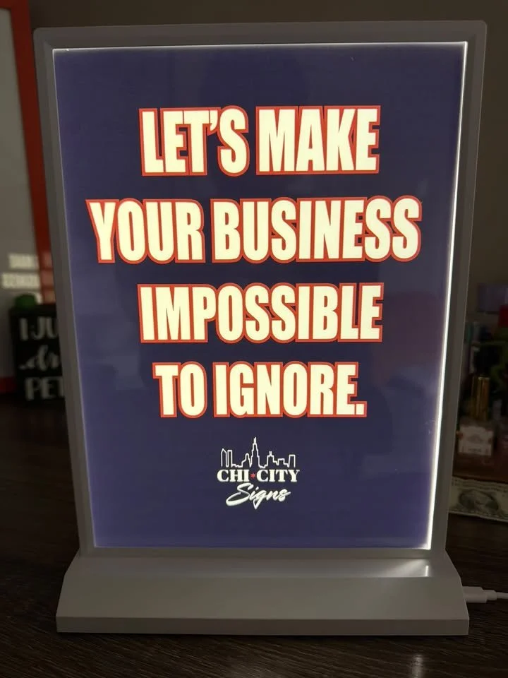 Illuminated light box sign reading Let’s make your business impossible to ignore