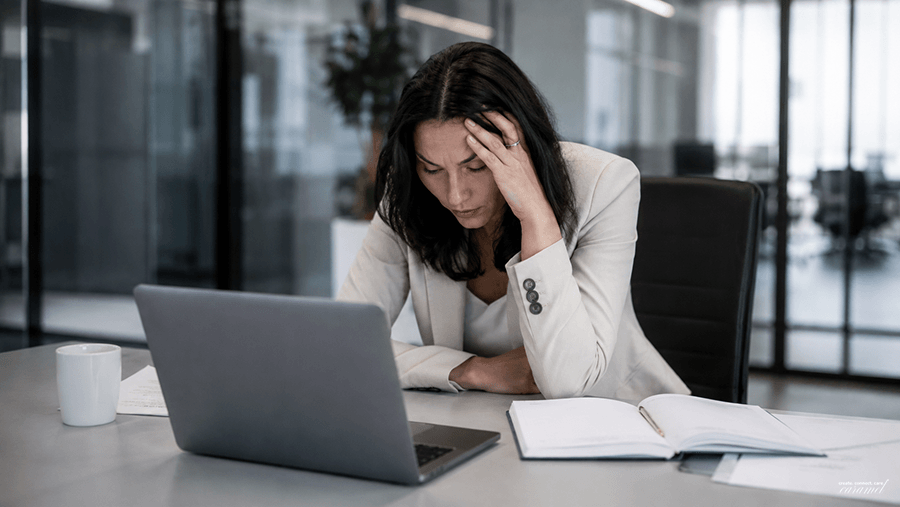 Zmęczona pracowniczka przy laptopie w nowoczesnym biurze
