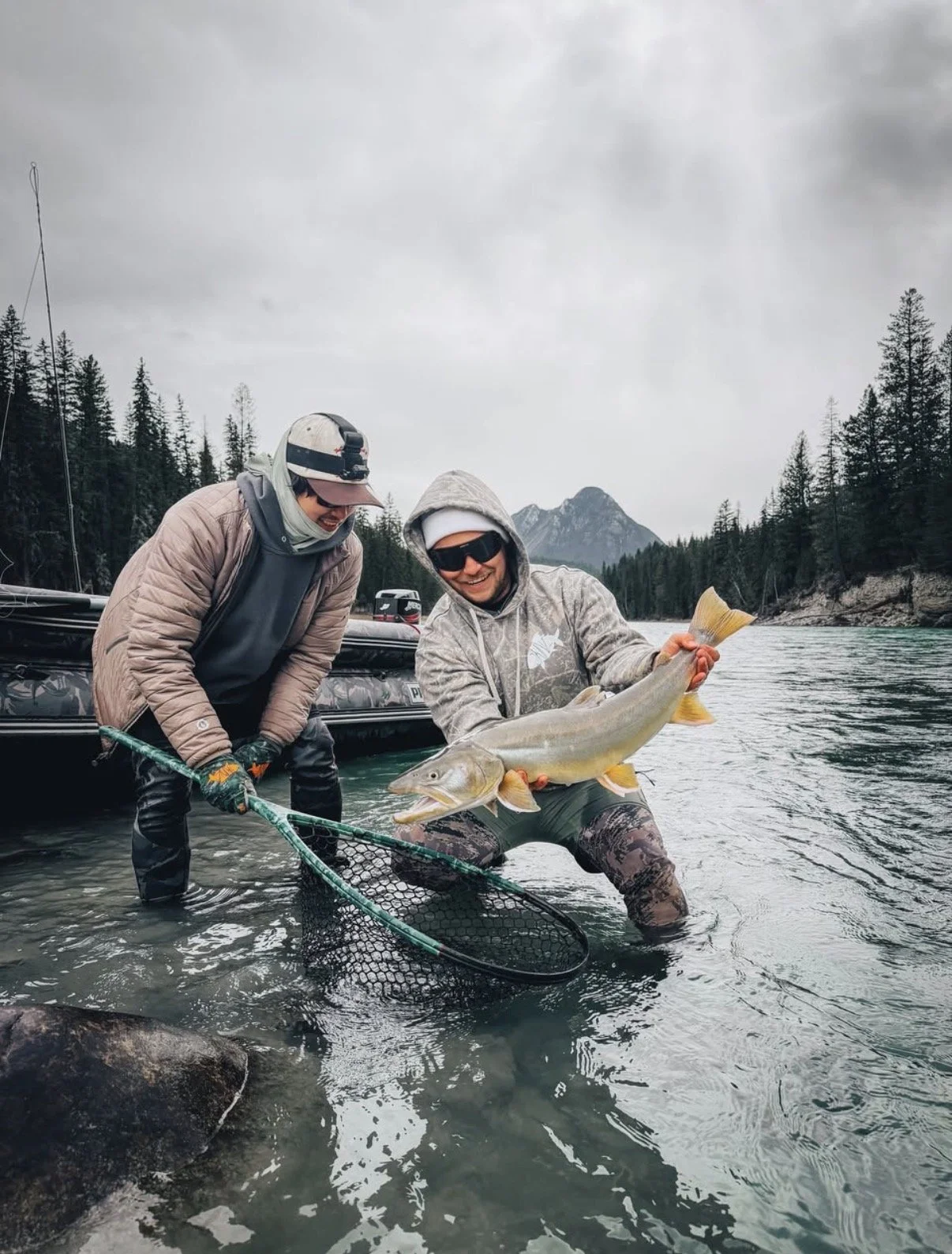 Angler in a Backcountry Skinz hoodie holding a fish