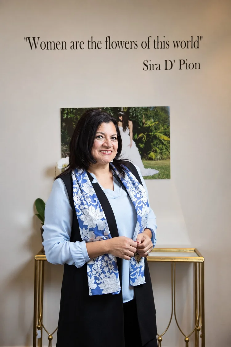 Sira D’ Pion, bridal designer and founder, in her atelier wearing a blue floral scarf.