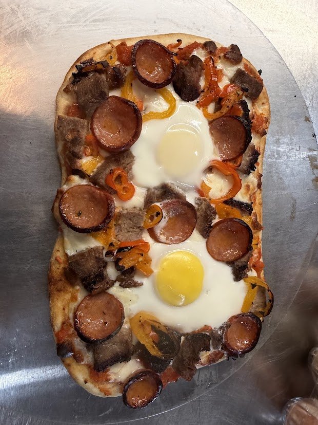 Vinland Clydesdale flatbread topped with eggs, sausage, meat and peppers
