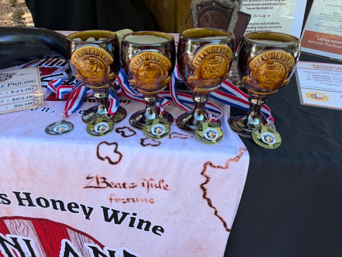 Four Texas Mead Cup goblets and five medals displayed at the Vinland Meads booth.