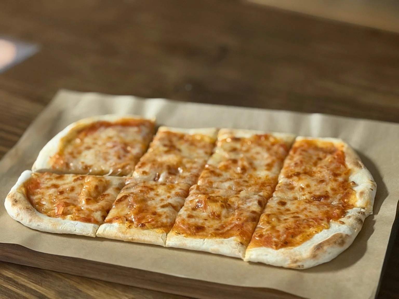Vinland Cheese Flatbread cut into eight pieces on a wooden board