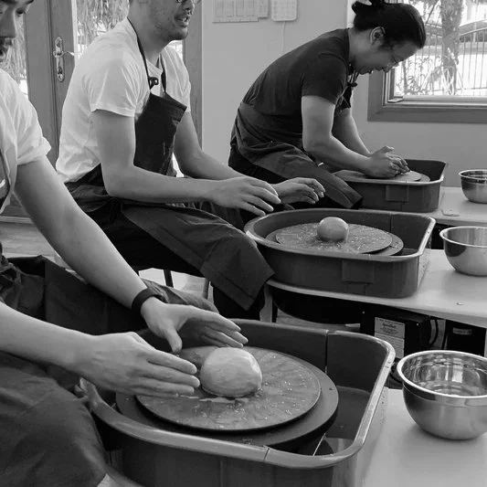 Hands shaping clay on a pottery wheel