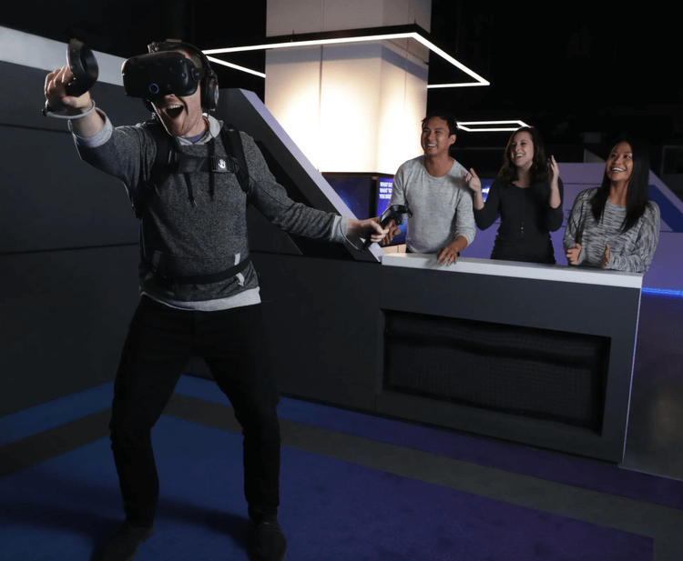 Guest mid-experience in an IMAX VR pod, others watching