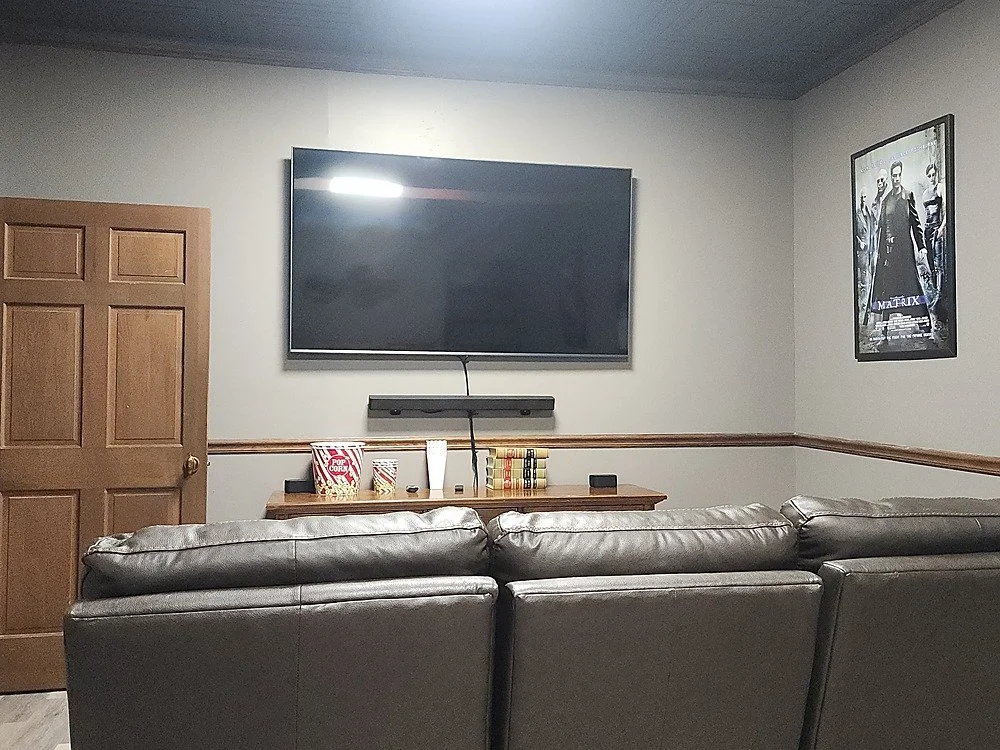 The home theatre room at Your Boutique Hotel showing the front of the room with a mounted TV and movie posters