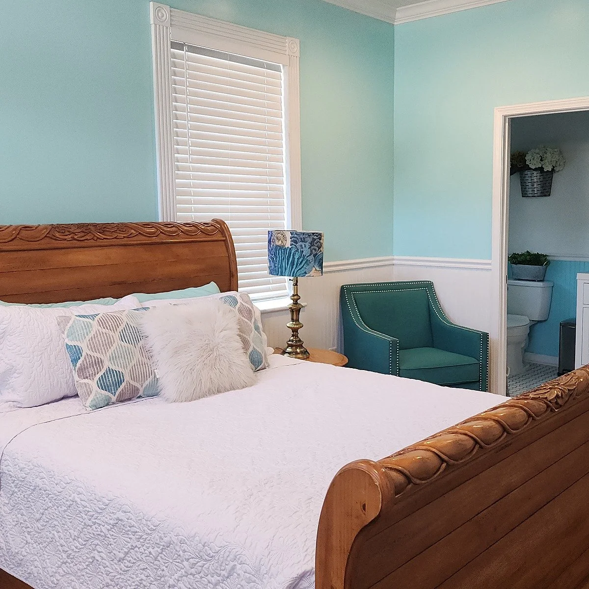 The Coastal Suite, a guest suite with seafoam blue walls and a wood sleigh bed