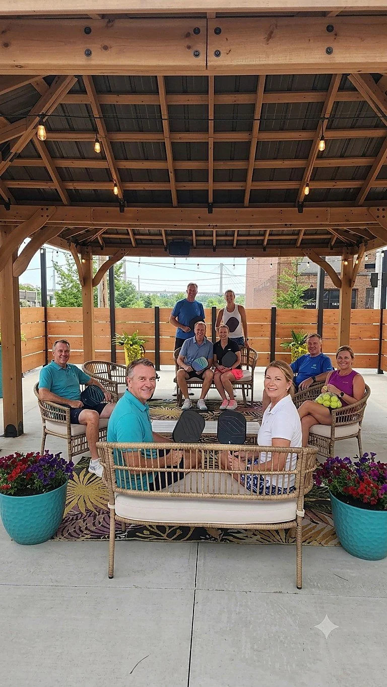 Group relaxing courtside under the gazebo with pickleball paddles at Your Boutique Hotel