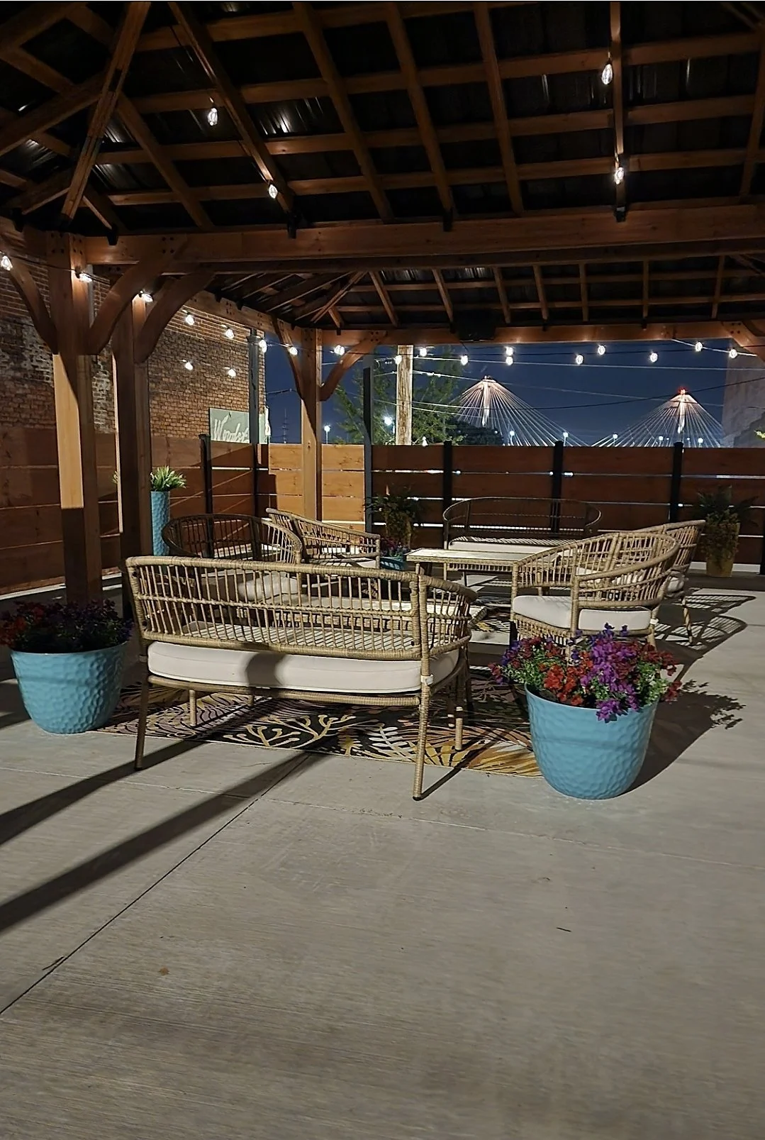 The courtside patio at Your Boutique Hotel at night, with string lights and the Clark Bridge glowing in the background
