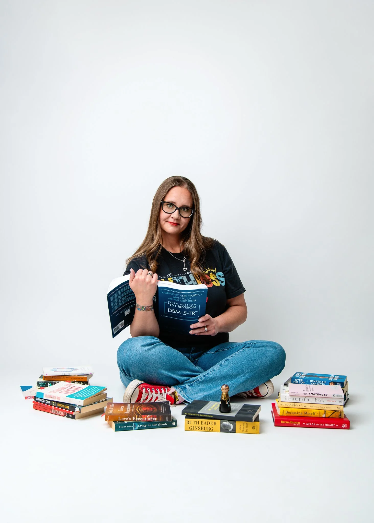 Stacy Reynolds, LMFT-Associate, seated with clinical texts including the DSM-5-TR — Brain & Heart Healing, Abilene TX