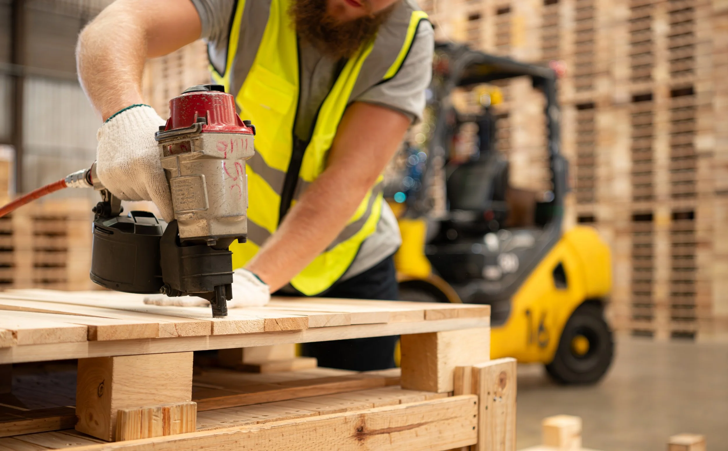 Professional pallet and crate consultation showing custom-designed wood pallets in a manufacturing warehouse.