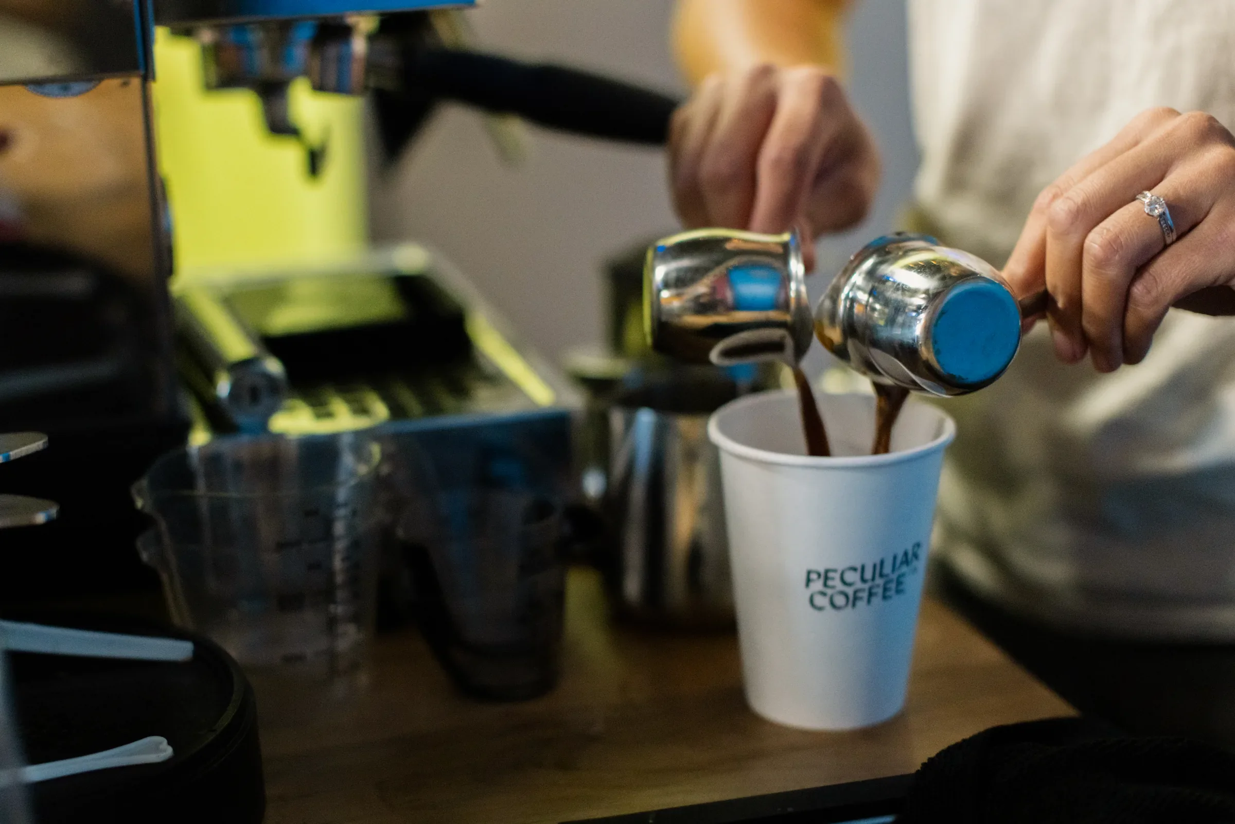 A double espresso pouring into a Peculiar Coffee branded cup at the espresso station