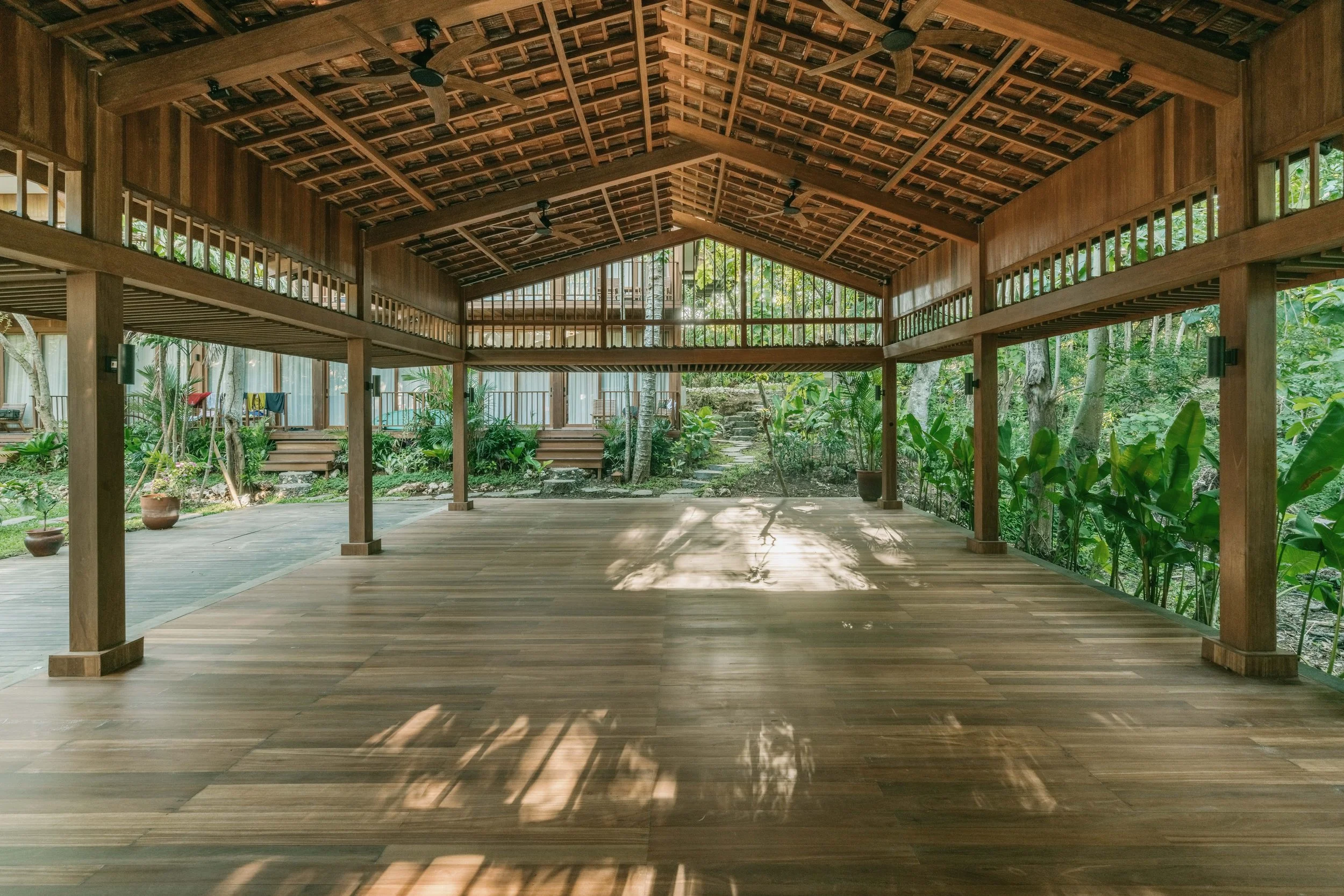 An open-air wooden yoga shala surrounded by tropical garden