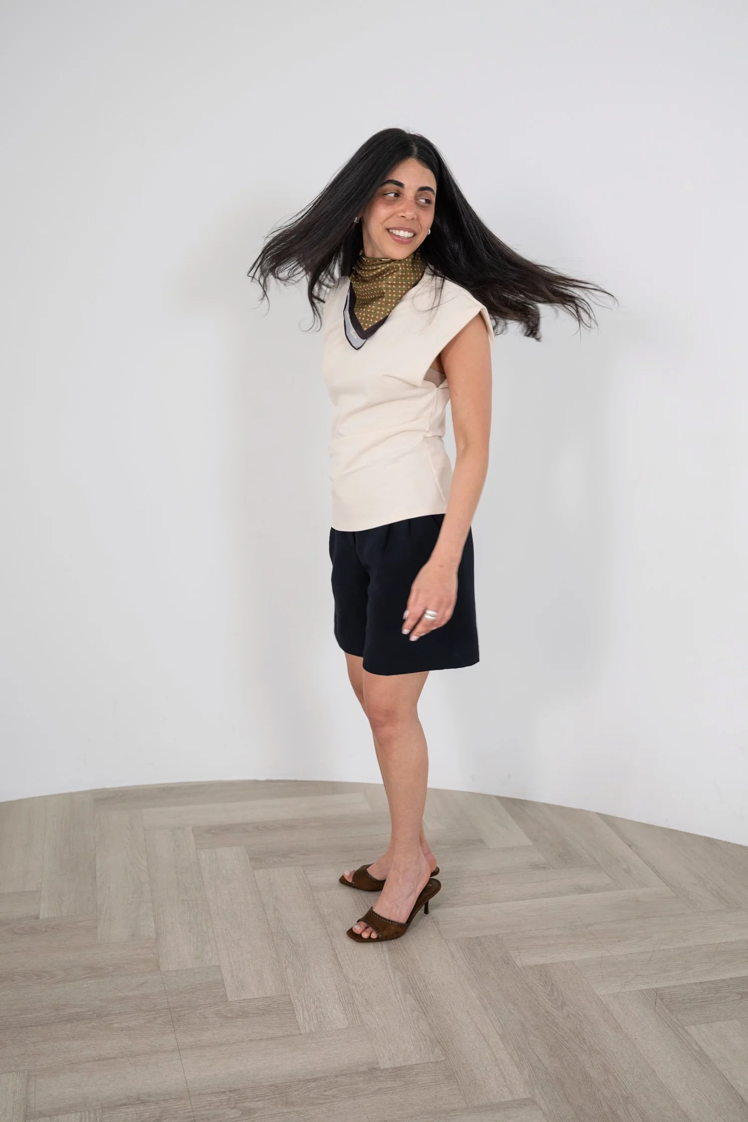 Candid portrait of a smiling designer in a cream sleeveless top