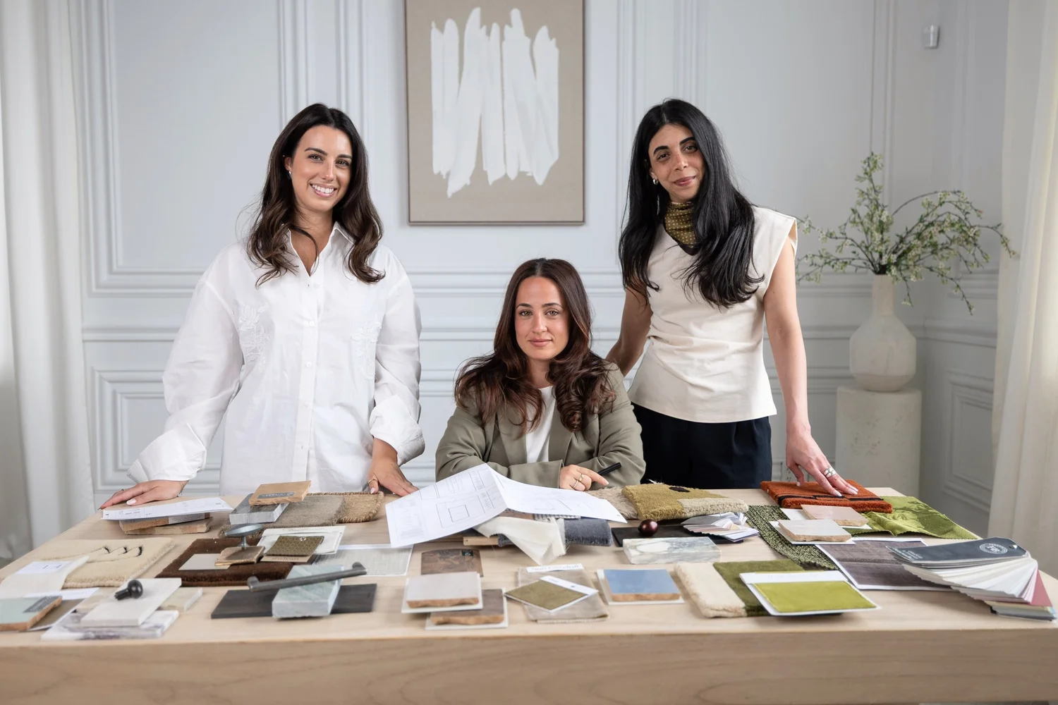 Three interior designers gathered around a table of material samples