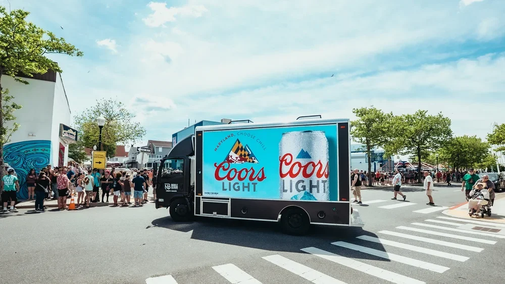 Digital LED mobile billboard truck displaying a bright campaign advertisement at a major public event