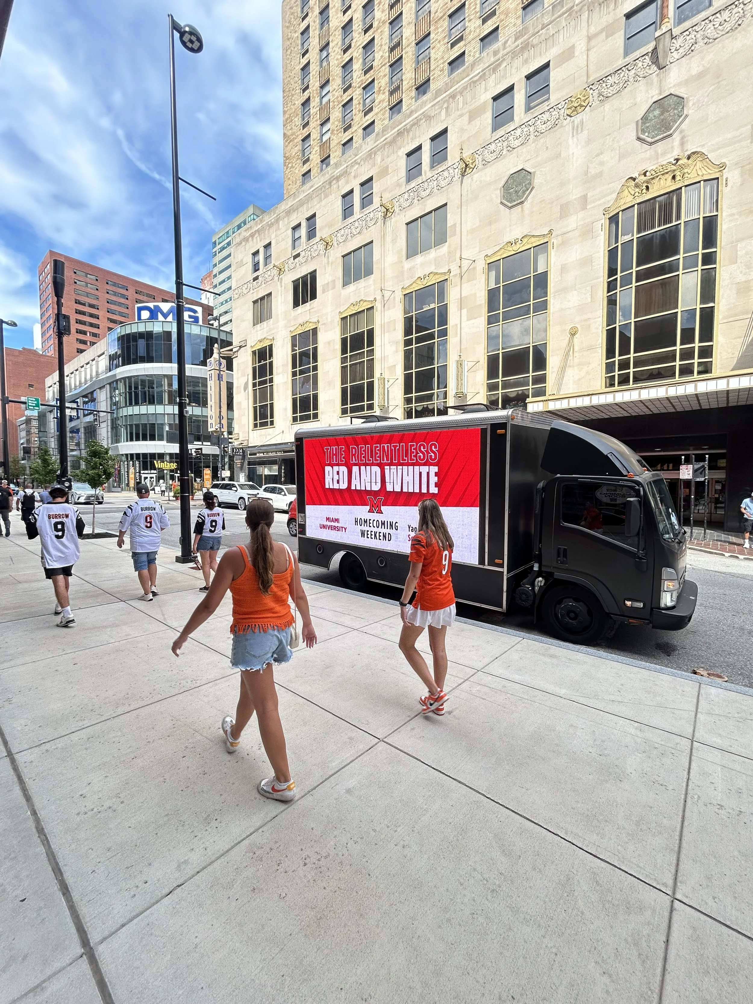 LED mobile billboard truck in slow game day traffic near Paycor Stadium in Cincinnati with pedestrians nearby