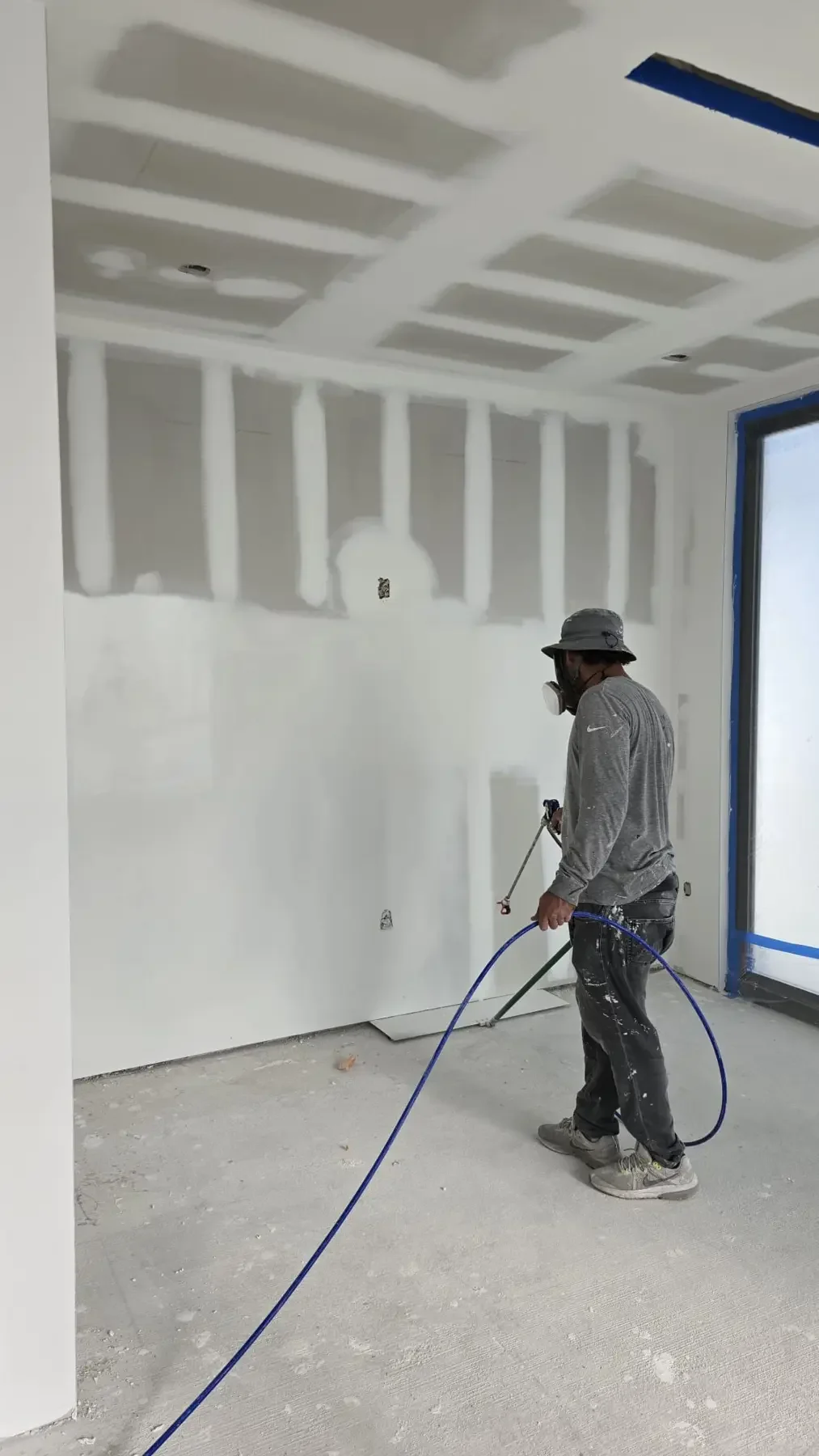 Professional painter spraying interior walls in a Miami home