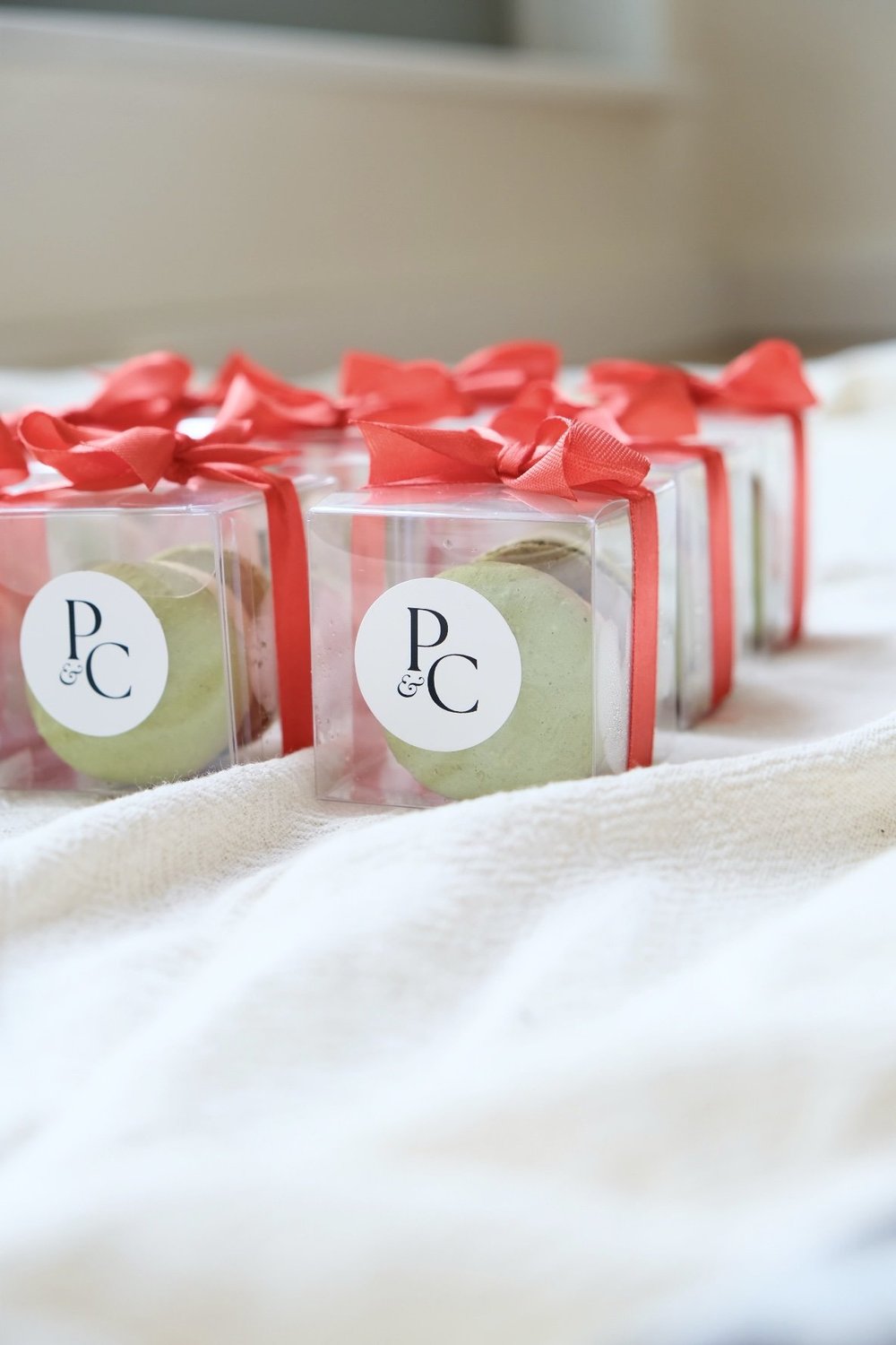 Single-macaron gift boxes with a monogram sticker and ribbon