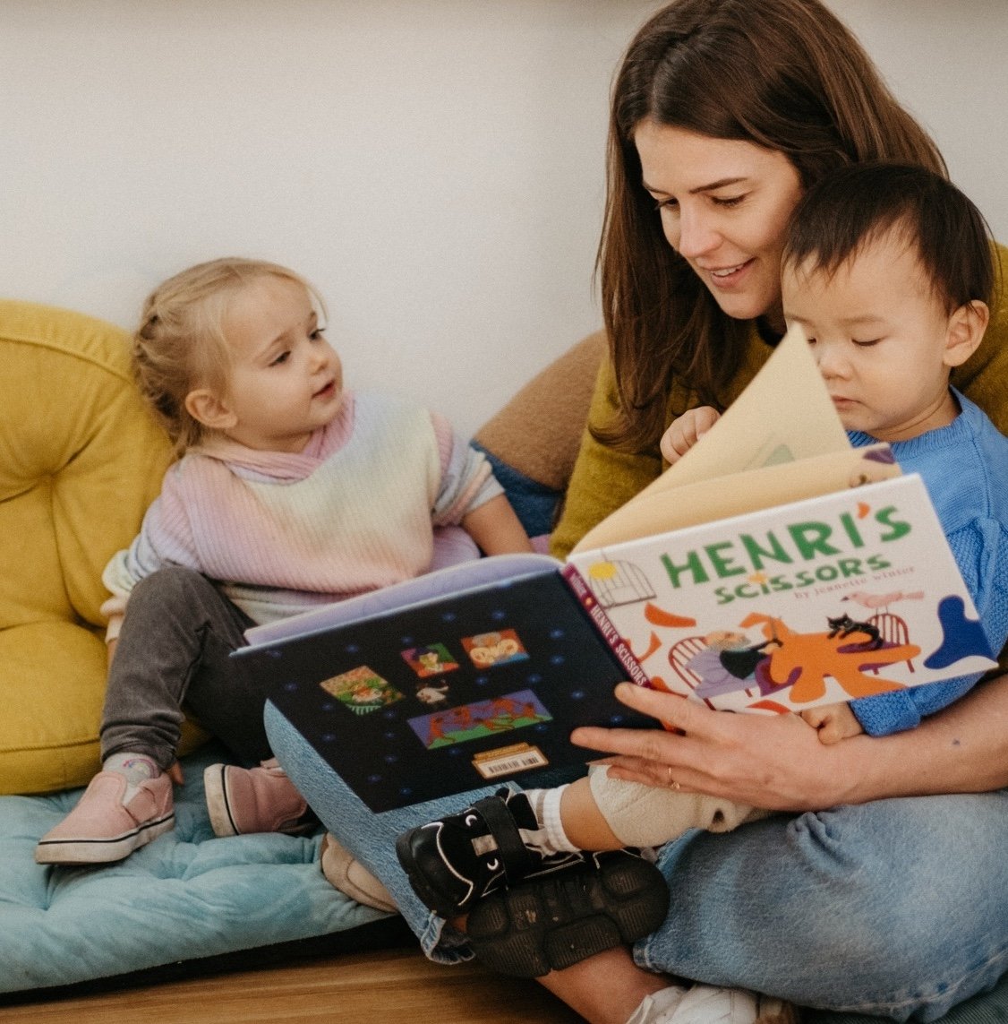 An educator reading a picture book with young children.