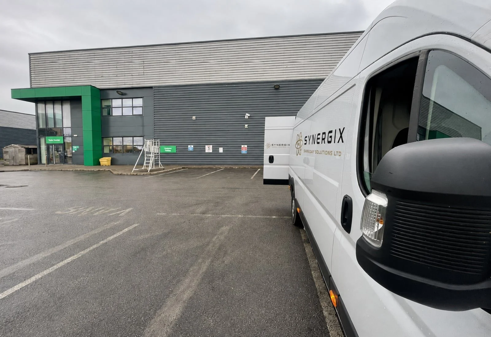Synergix-branded courier van outside a warehouse on a wet day.