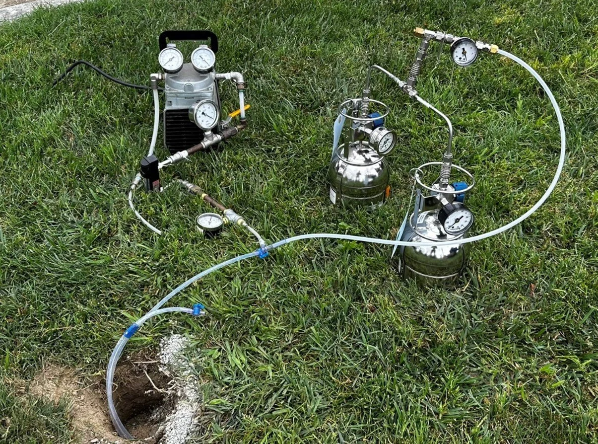 Soil gas sampling equipment including vacuum pump and stainless steel Summa canisters connected to a monitoring well for subsurface vapor investigation