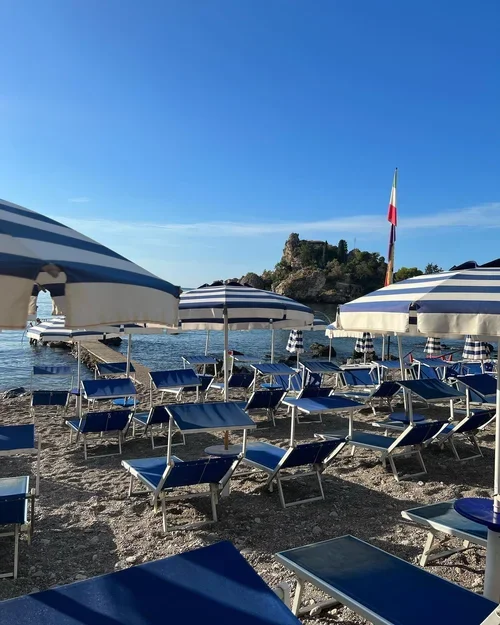 Rows of striped umbrellas on the beach in Taormina, Sicily