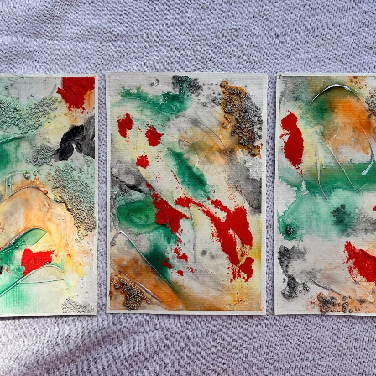 Three artworks from the “Built Of Light” series in sunlight – bold reds, greens and shimmering silver symbolizing protection, clarity and energetic boundaries.