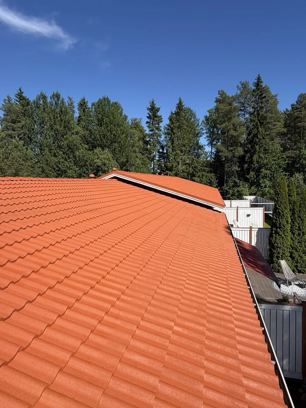 Rivitalon tiilikatto maalattuna tasaisen punaiseksi, taustalla metsää