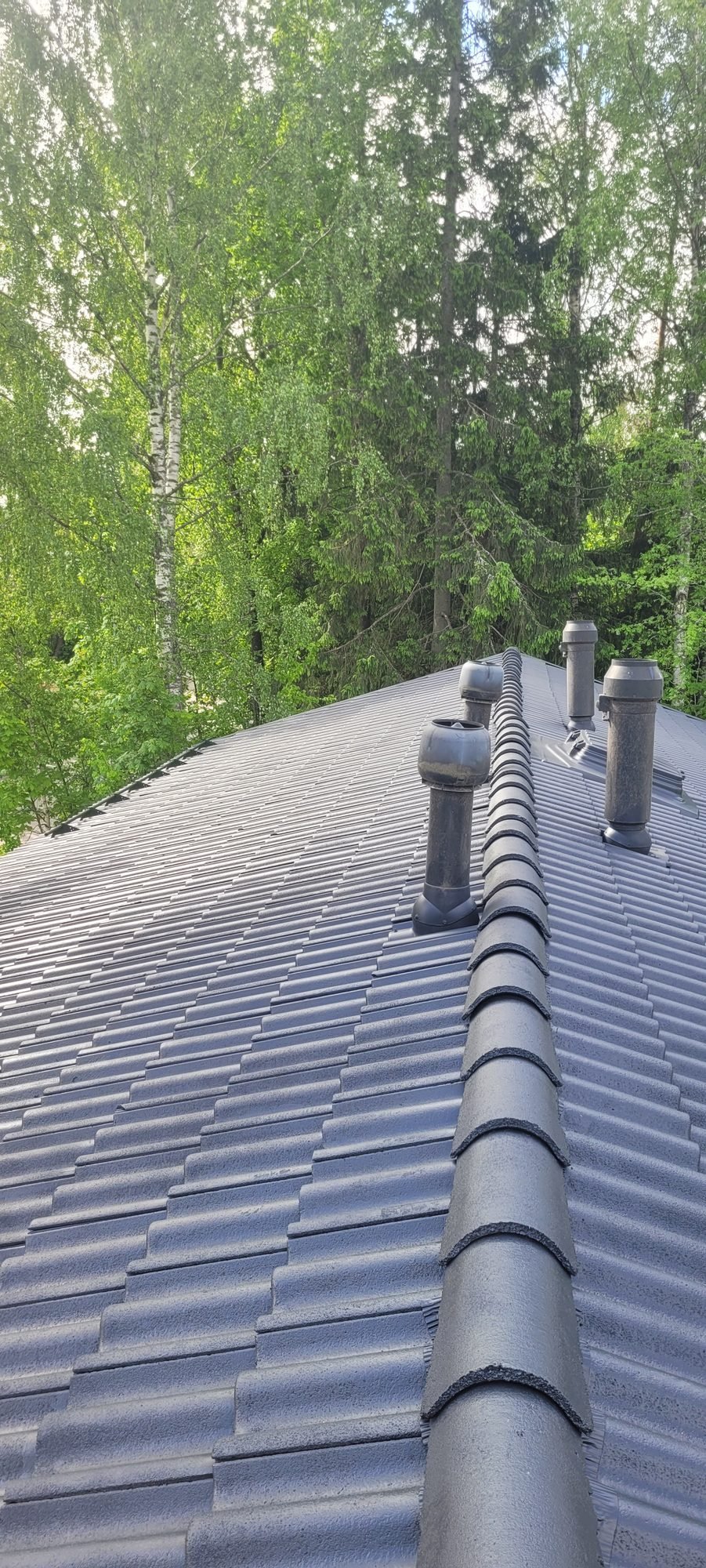 Pinnoitettu tumma betonitiilikatto harjalta kuvattuna