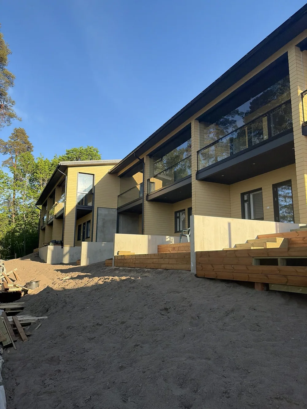 Valmiiksi maalattu keltainen rivitalo ja lasitetut parvekkeet iltavalossa