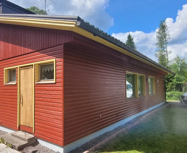 Punaiseksi maalattu puutalo keltaisin listoin valmiina