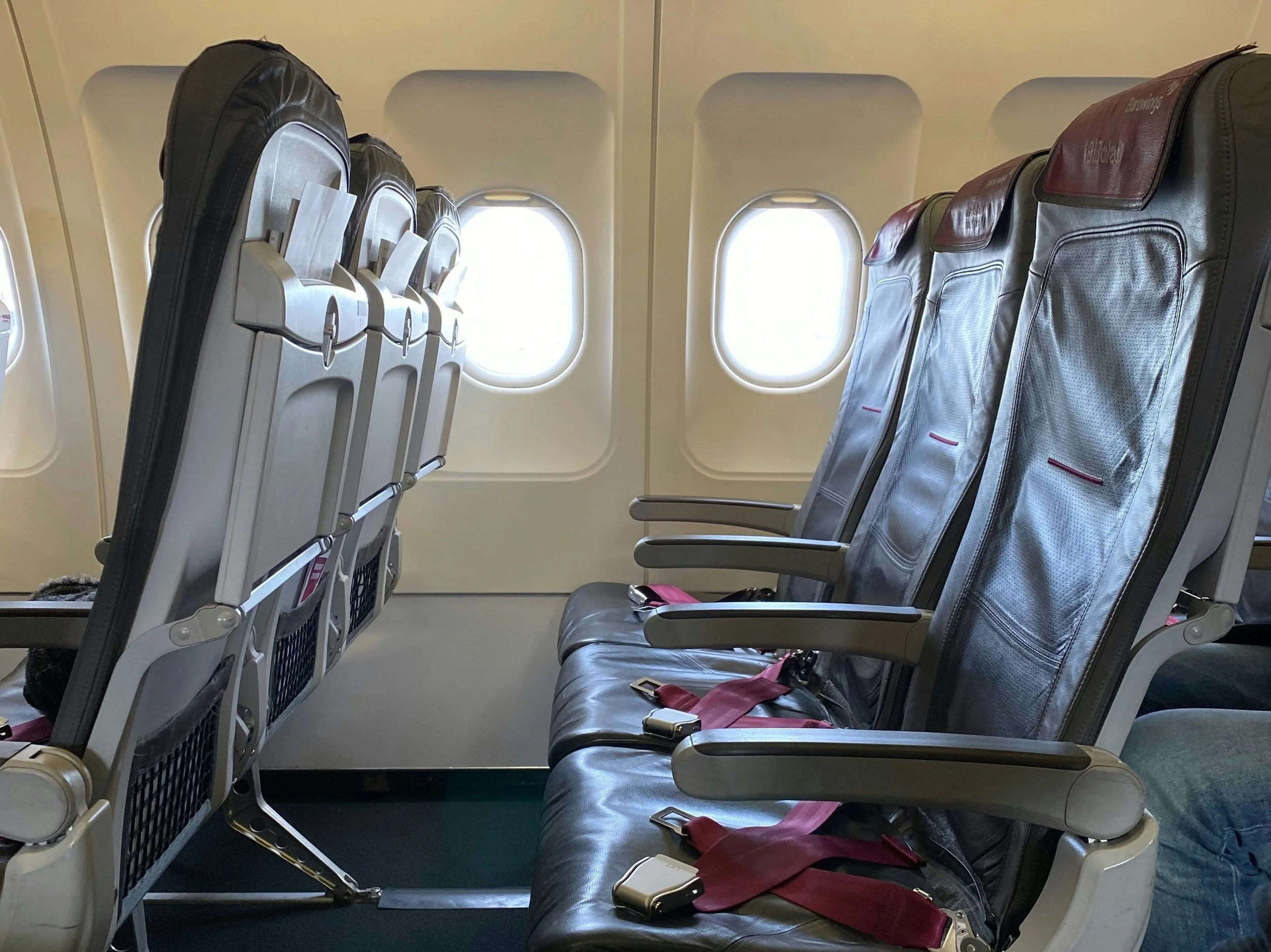 Three-seat airplane row showing how economy seating can feel different by aircraft and airline