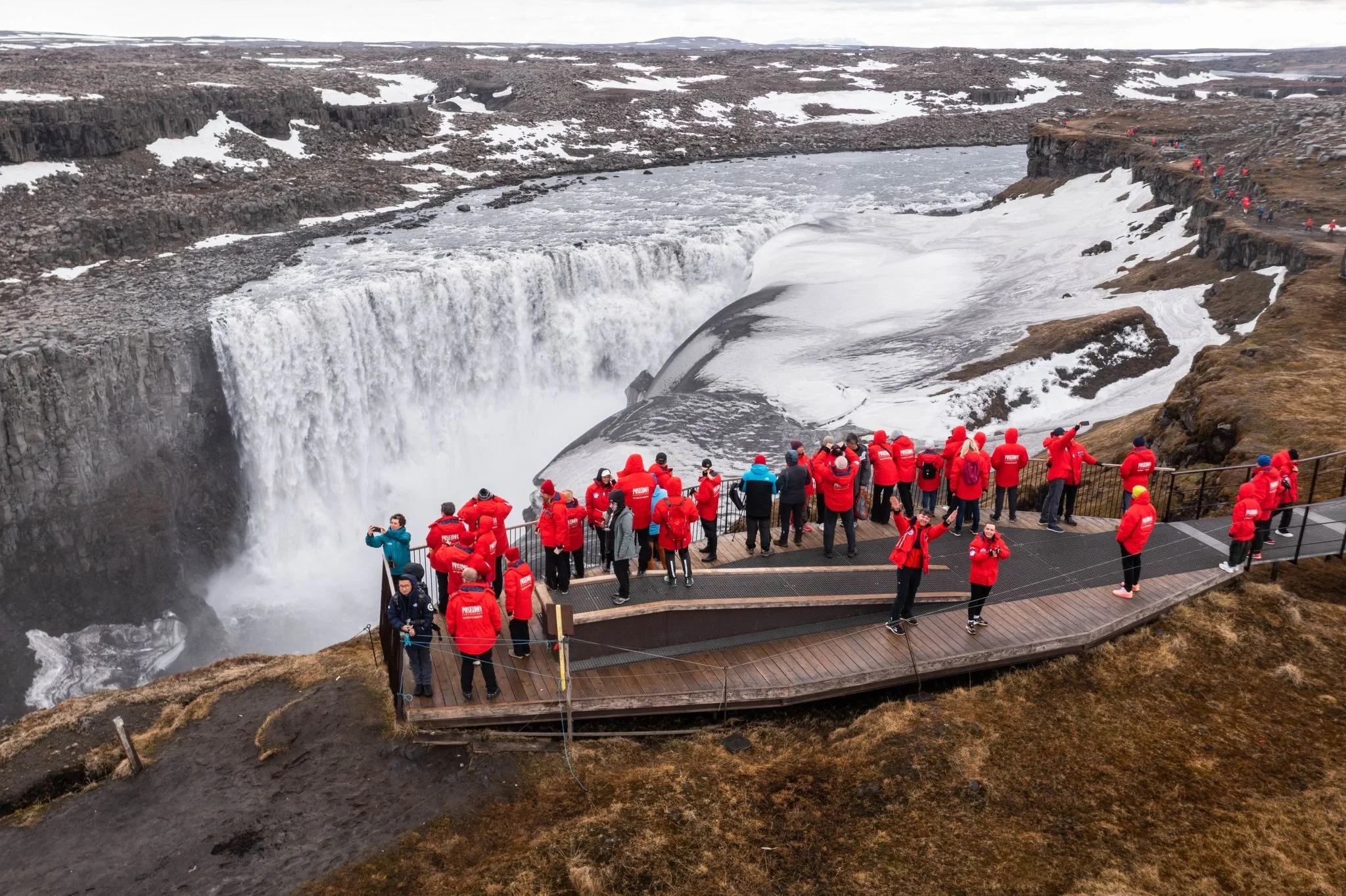 Expedition travelers in red parkas visiting a remote waterfall
