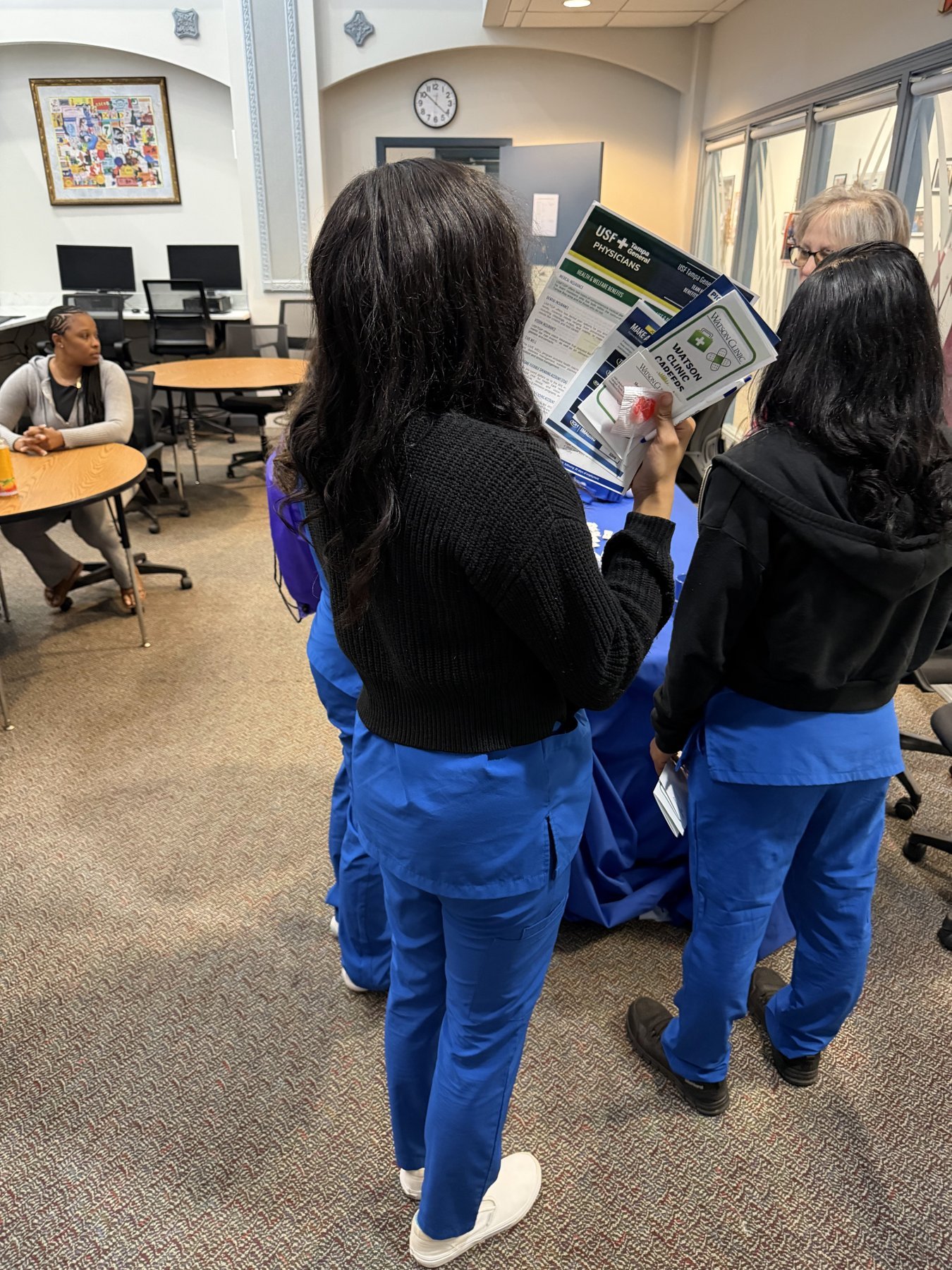 Students in blue scrubs reviewing employer recruiting brochures at a Southern Technical College career fair.