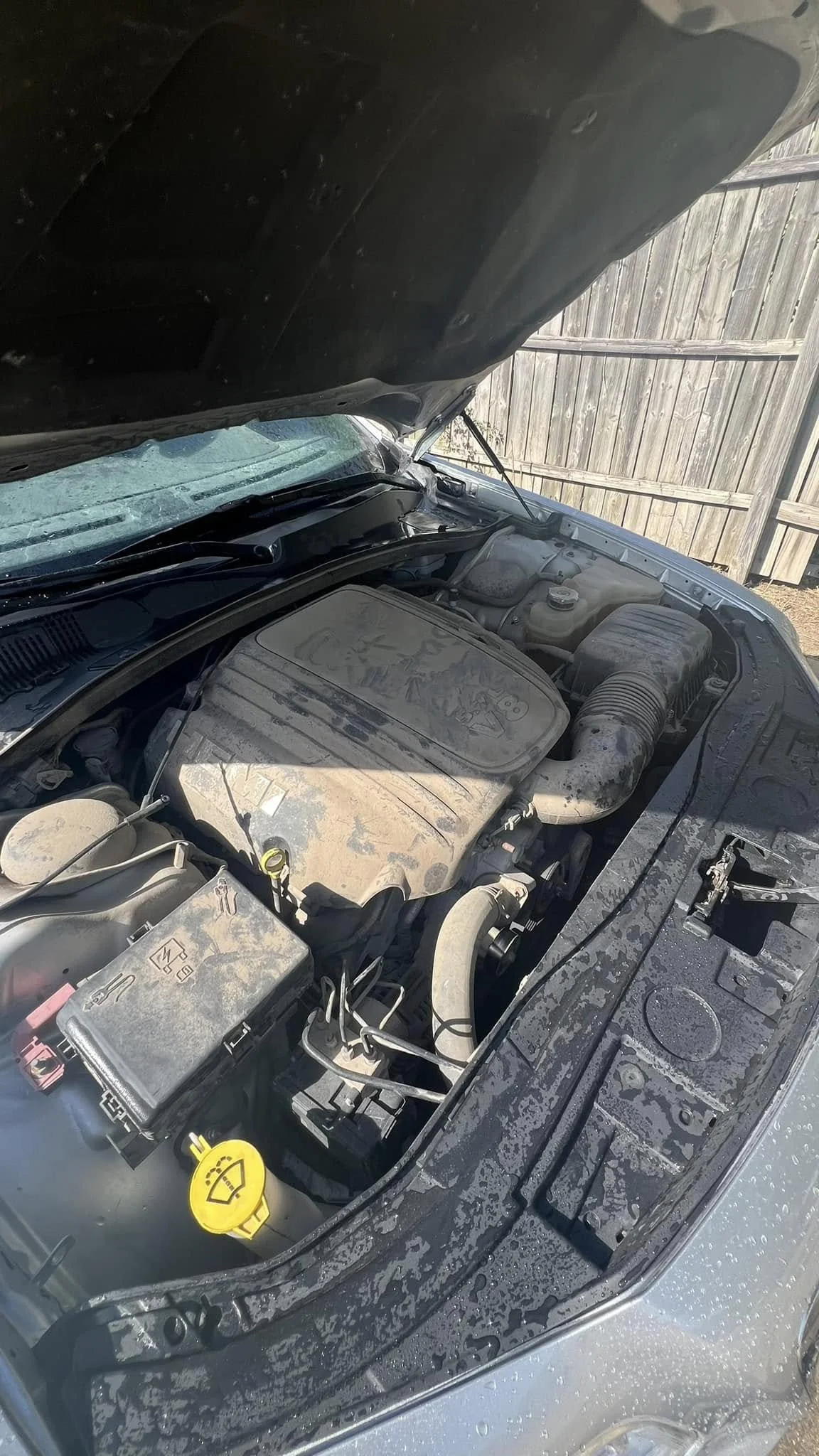 Before: neglected engine bay with dust and residue on covers and plastics – Lincoln NE detailer