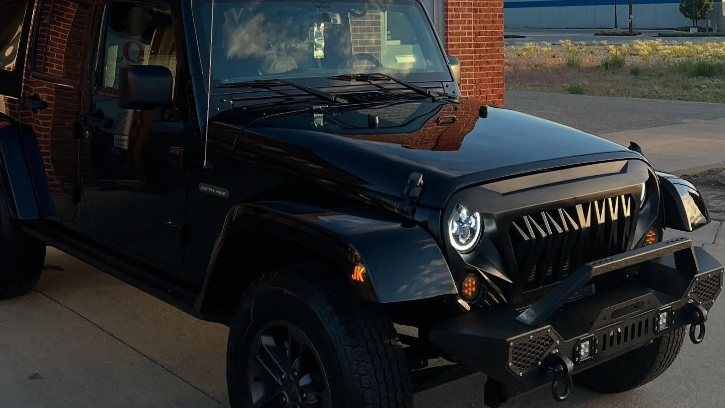 Glossy black car hood reflecting clear blue sky at MC Auto Detailing in Lincoln after wax treatment