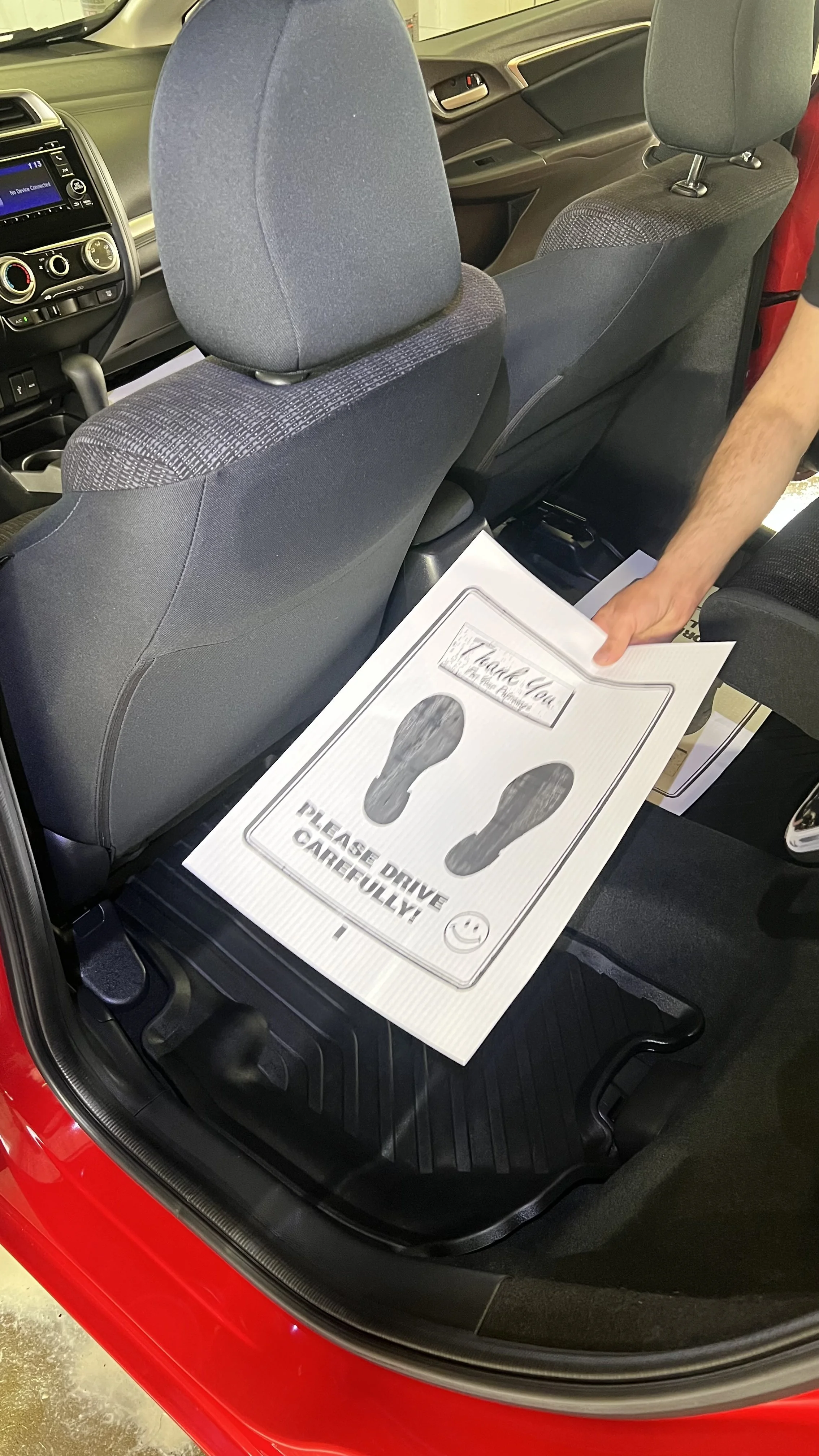 Placing paper floor mat in freshly detailed Honda Fit MC Auto Detailing Lincoln