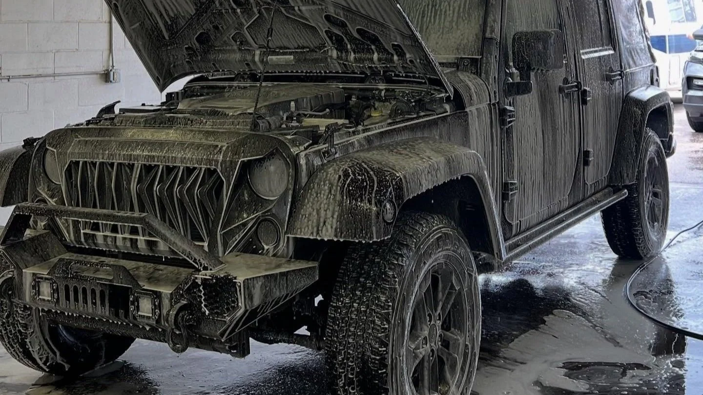MC Auto Detailing technician hand-washing a blue sedan exterior in Lincoln, Nebraska